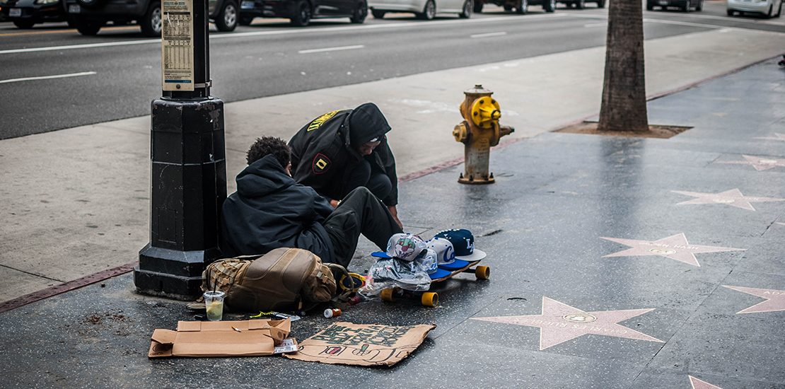 Two individuals experiencing homelessness sitting on Hollywood Boulevard