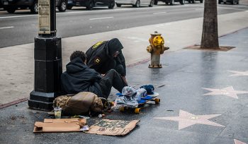 Image is on Hollywood Walk of Fame with two people experiencing homelessness sitting with their belongings