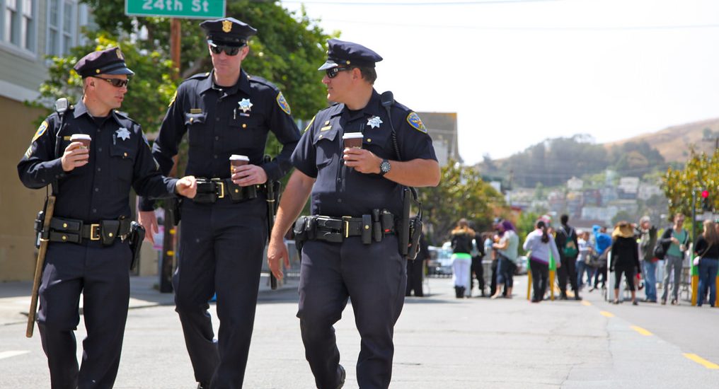 Image of three police officers walking on the street with coffee cups