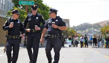 Image of three police officers walking on the street with coffee cups