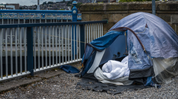 Image of tent on the road by a river belonging to an individual experiencing homelessness