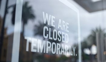 Glass door of a business. Sign on front says "WE ARE CLOSED TEMPORARILY"