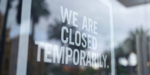 Store door with sign saying "we are closed temporarily"