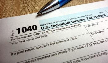US tax form 1040 and pen on wooden table