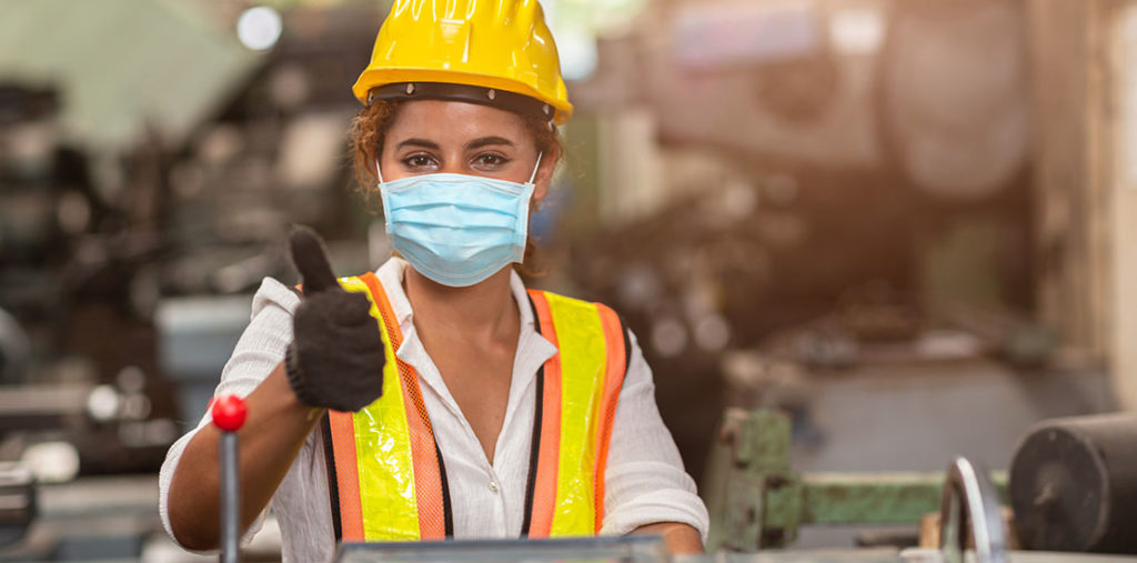 Female construction working wearing face masking holding thumbs up
