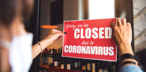 Worker hanging sign saying "sorry we're closed due to coronavirus"