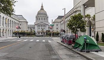 Image of street in front of San Francisco City Hall. There are 3 tents on the right sidewalk.