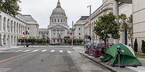 Image of street in front of San Francisco City Hall. There are 3 tents on the right sidewalk.