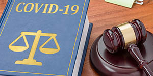 Picture of a law book that says COVID 19 on the cover and shows legal scales with a gavel next to it.