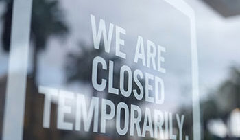 A sign on a store door says "WE ARE CLOSED TEMPORARILY"