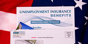 Image shows letter from EDD with unemployment insurance EBT card + booklet. Appears to be sitting on American flag.