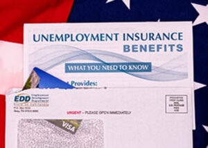 Image of an envelope from the Employment Development Dept, containing an Electronic Benefits Transfer card and a brochure about unemployment insurance benefits, all of which is sitting on an American flag.