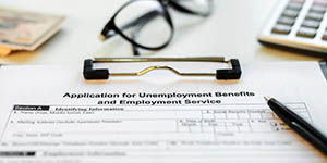 Photo shows an application for unemployment insurance and a pair of eyeglasses
